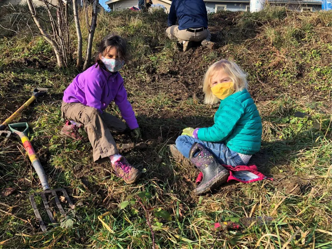 two kids in natural space helping plant a tree
