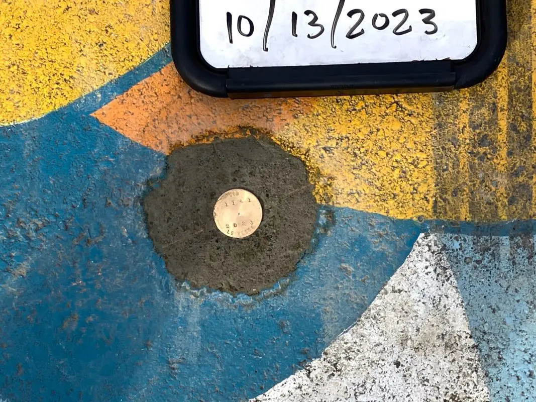 Very small metallic circle in the middle of a colorful mural. The circle says COB 2023 on it.