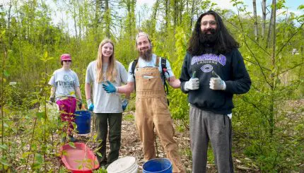 Four adults smile in the woods at a work party