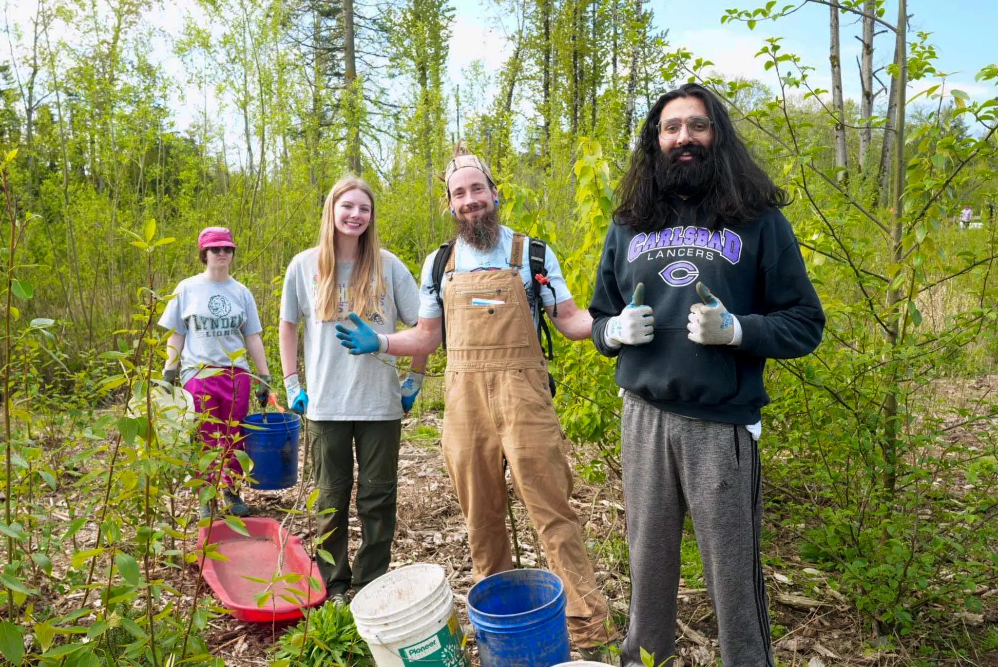 Four adults smile in the woods at a work party
