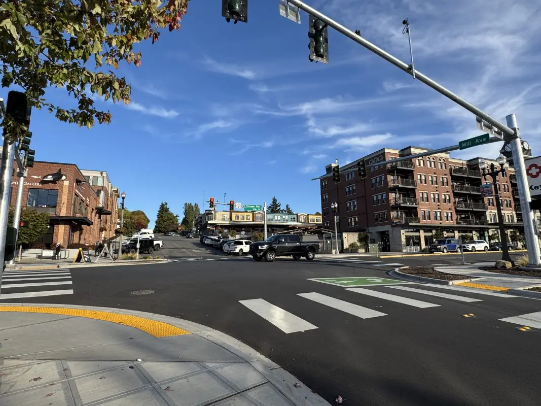 4-way traffic signal with vehicles driving through it on sunny day