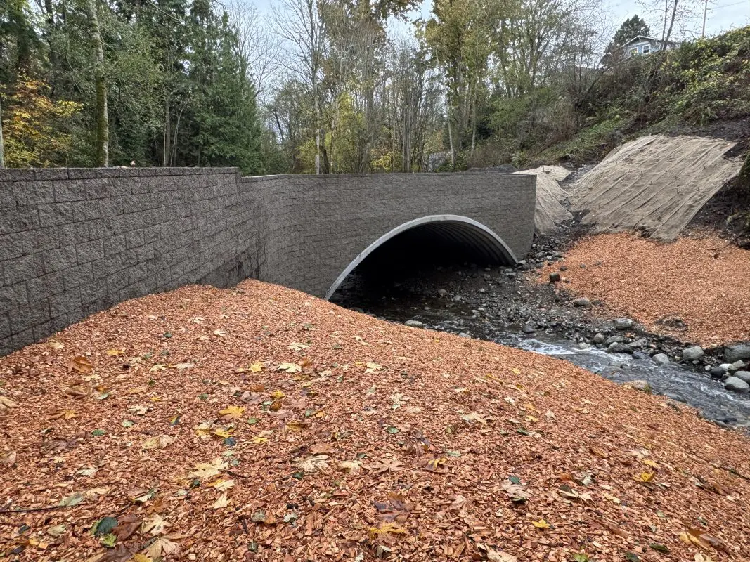Arch culvert over a creek with fresh mulch on streambanks