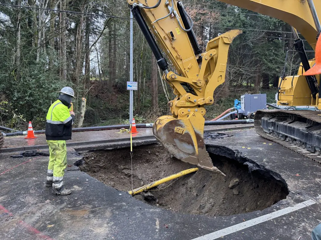Excavator digging underneath a damaged roadway