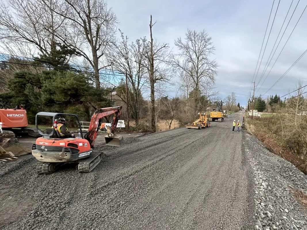 Excavator spreading gravel on roadway