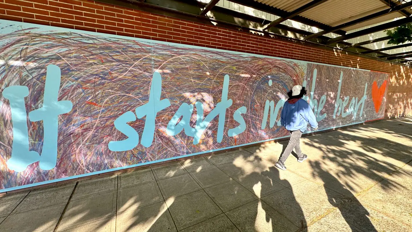 "It starts in the heart" mural creation. People created the mural with trike wheels covered in paint.