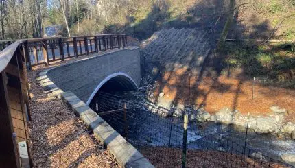 Large arch culvert with a creek flowing underneath it and new mulch on the streambanks