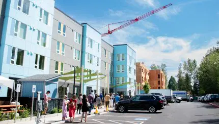 People walk in front of a large, new apartment building.
