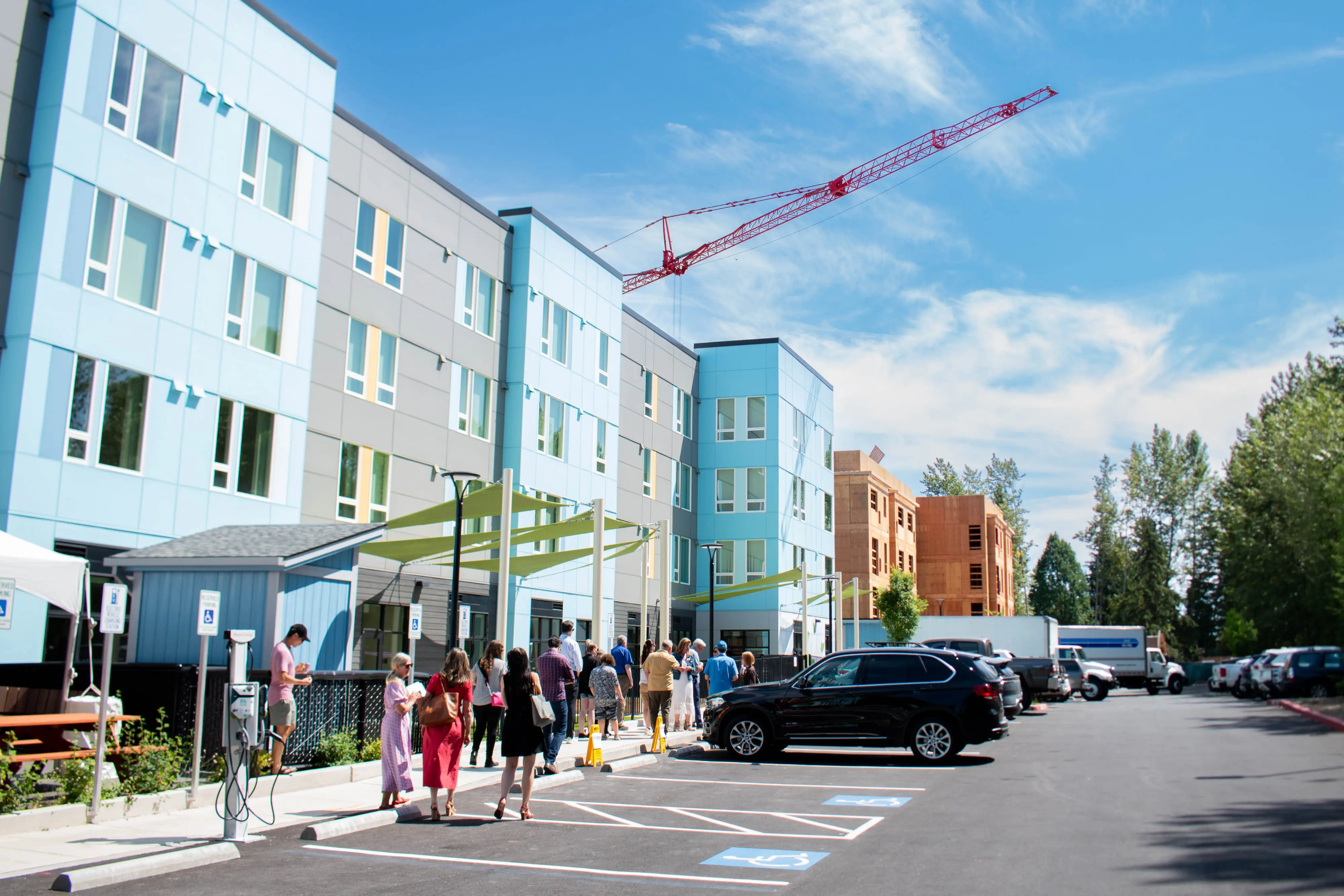 People walk in front of a large, new apartment building.