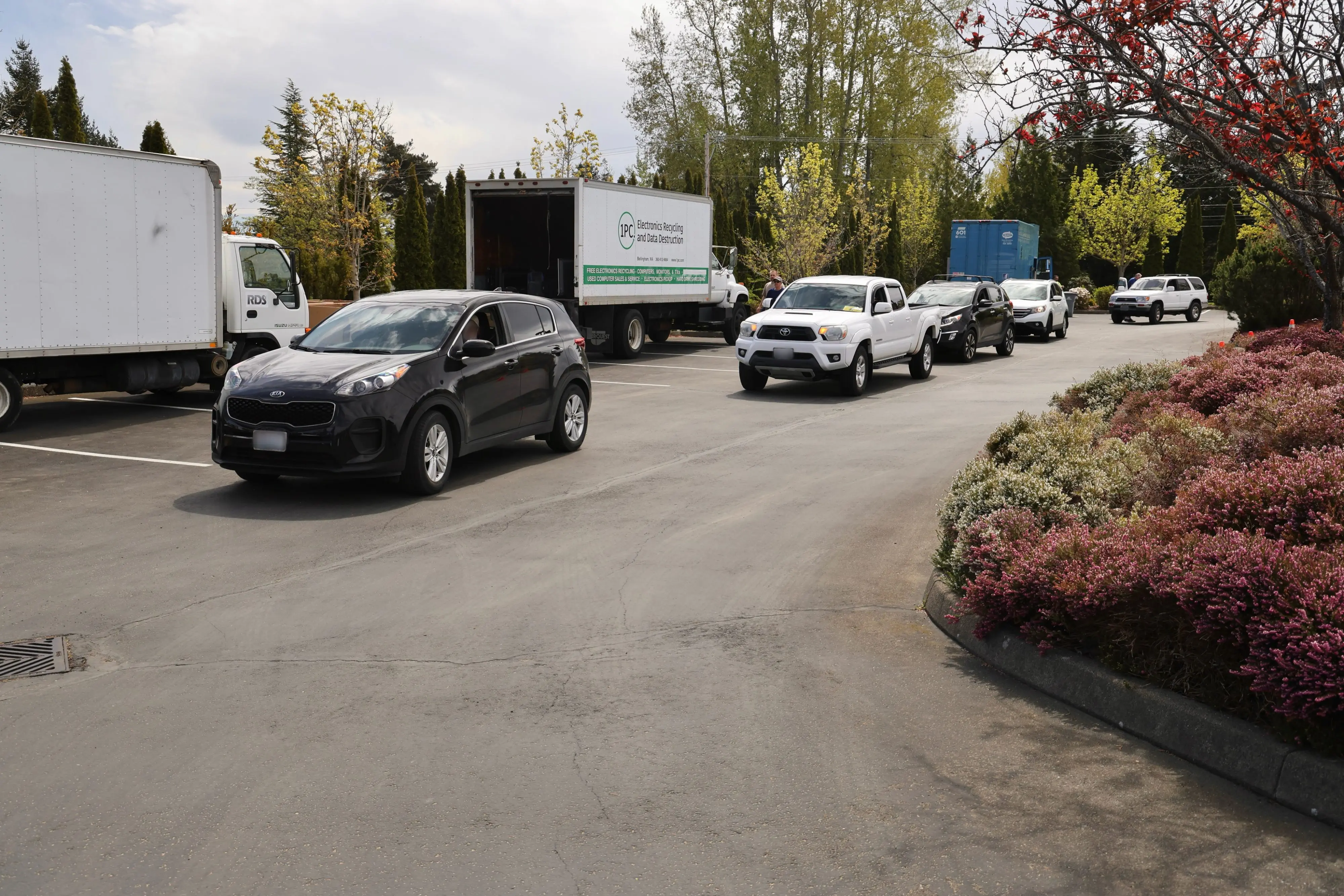 Cars lined up in a parking lot to drop off recycling items at different stations