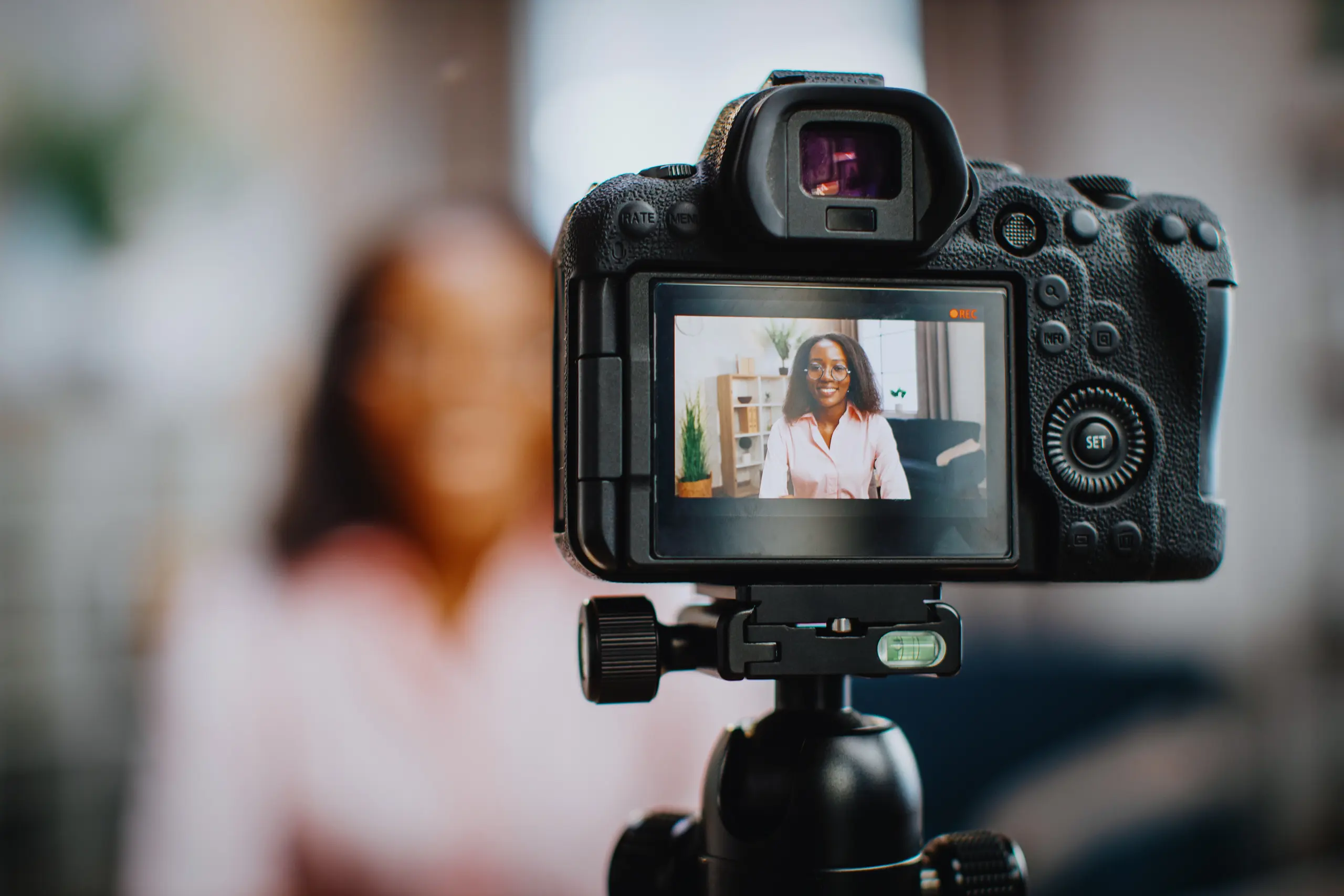 A woman is seen smiling through the viewfinder of a camera.