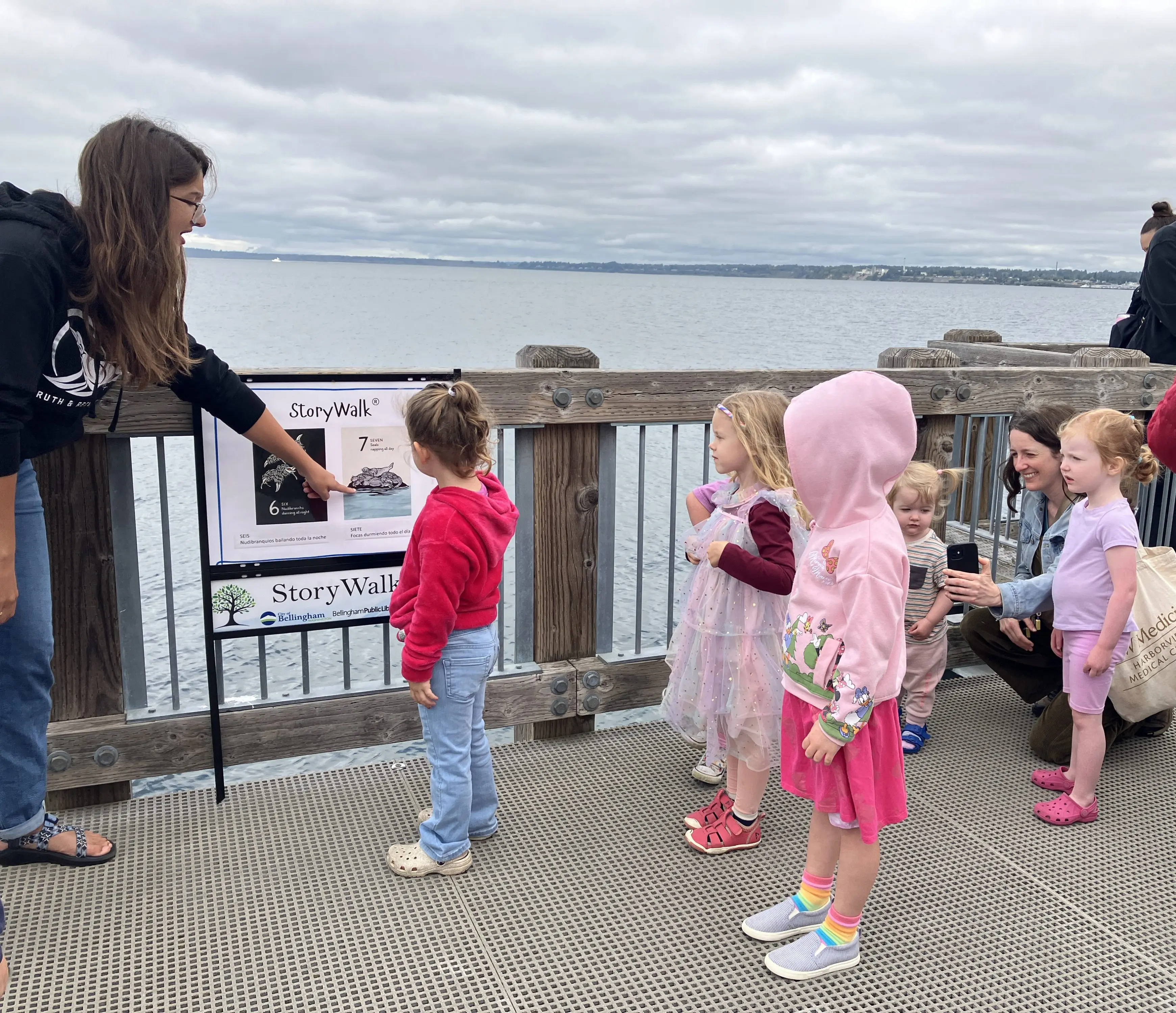 A woman explains a boardwalk sign to a group of young children