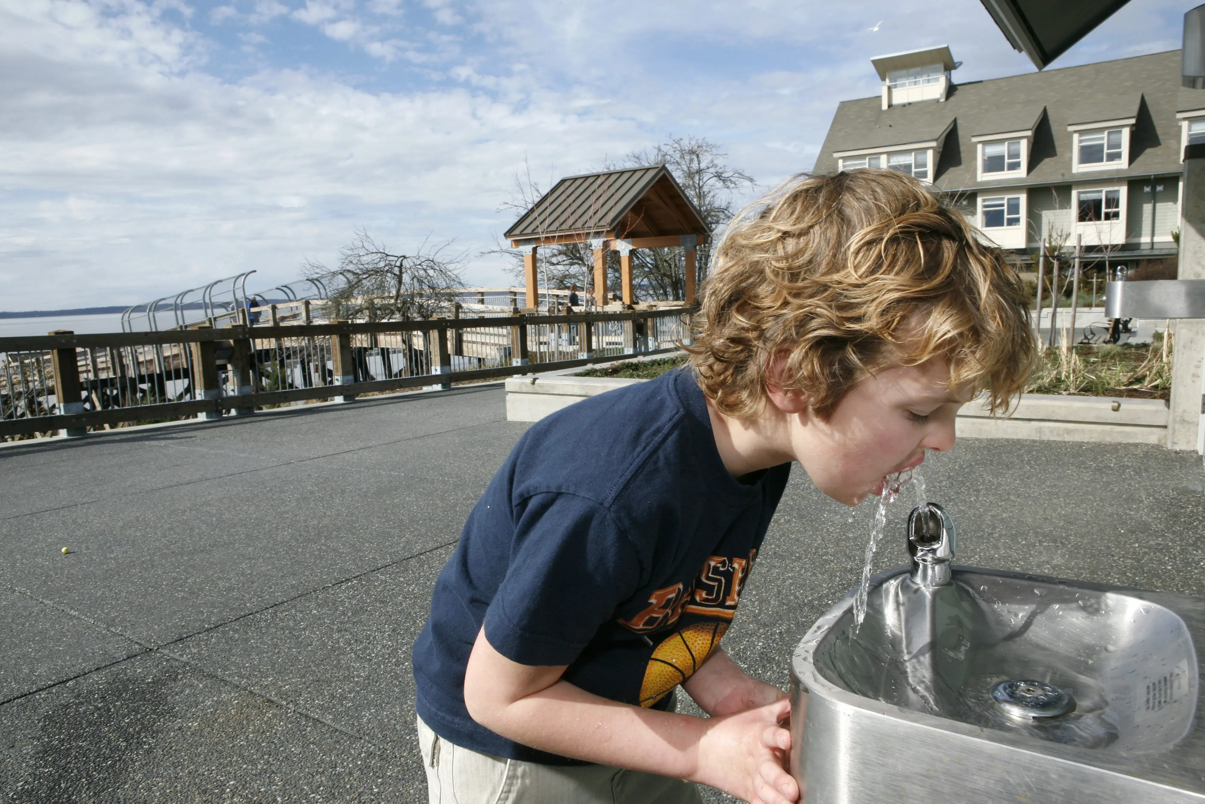 Boy drinking from water fountain outside