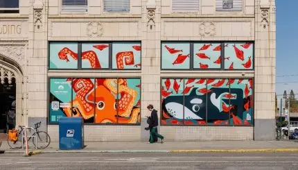 Commercial building with colorful sea-themed art in the large storefront windows in an urban area