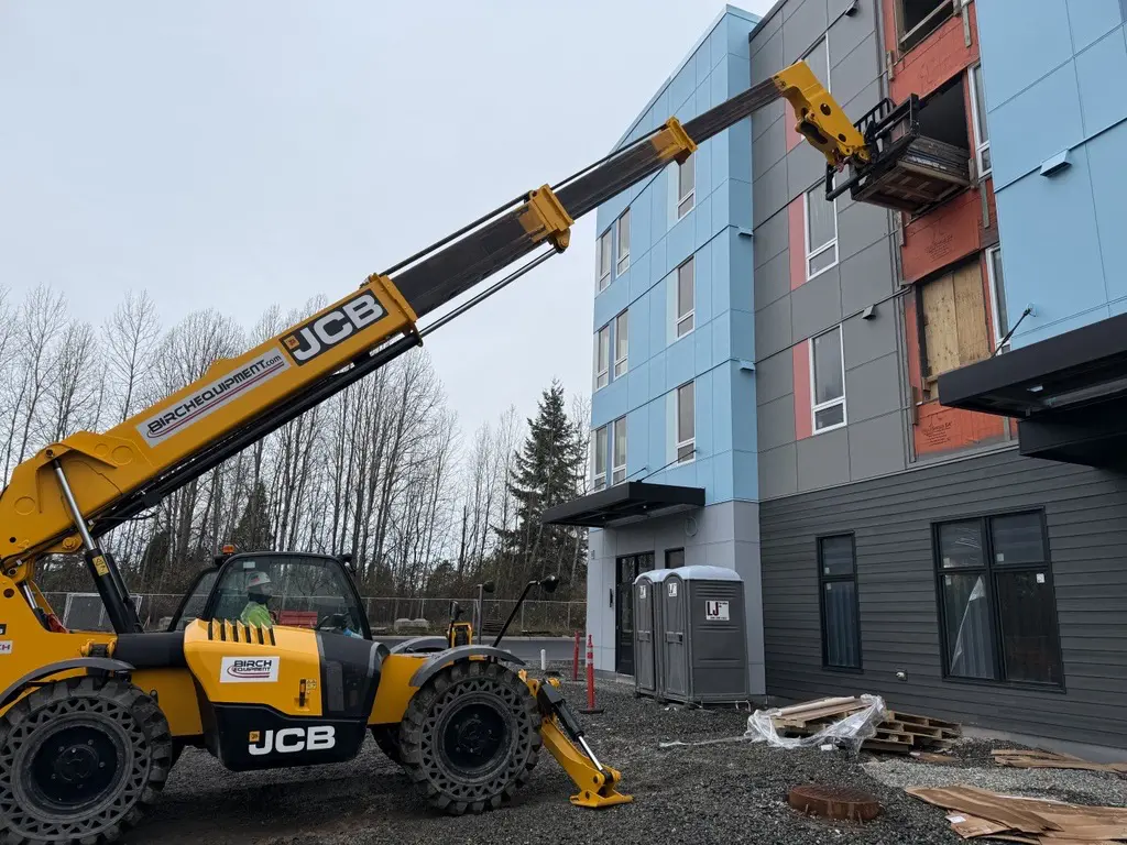 Construction vehicles work on an apartment building 