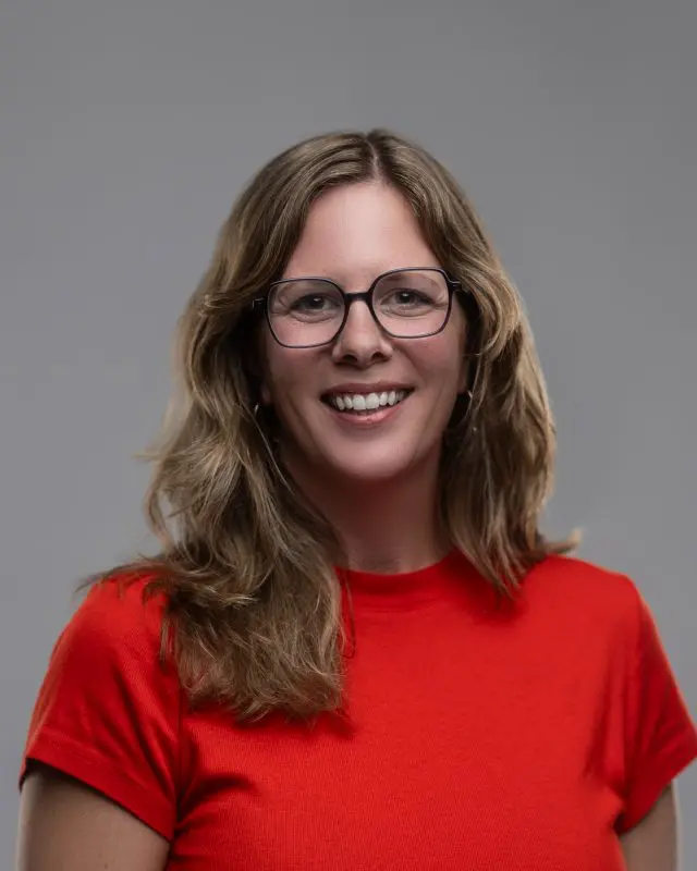 Professional headshot of a white woman in a red shirt