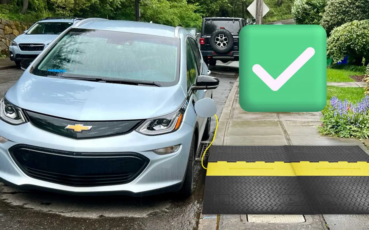 A parked electric vehicle with a charging cord under an approved cover.