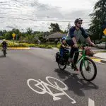 Man and young child riding on bike with older child riding near by