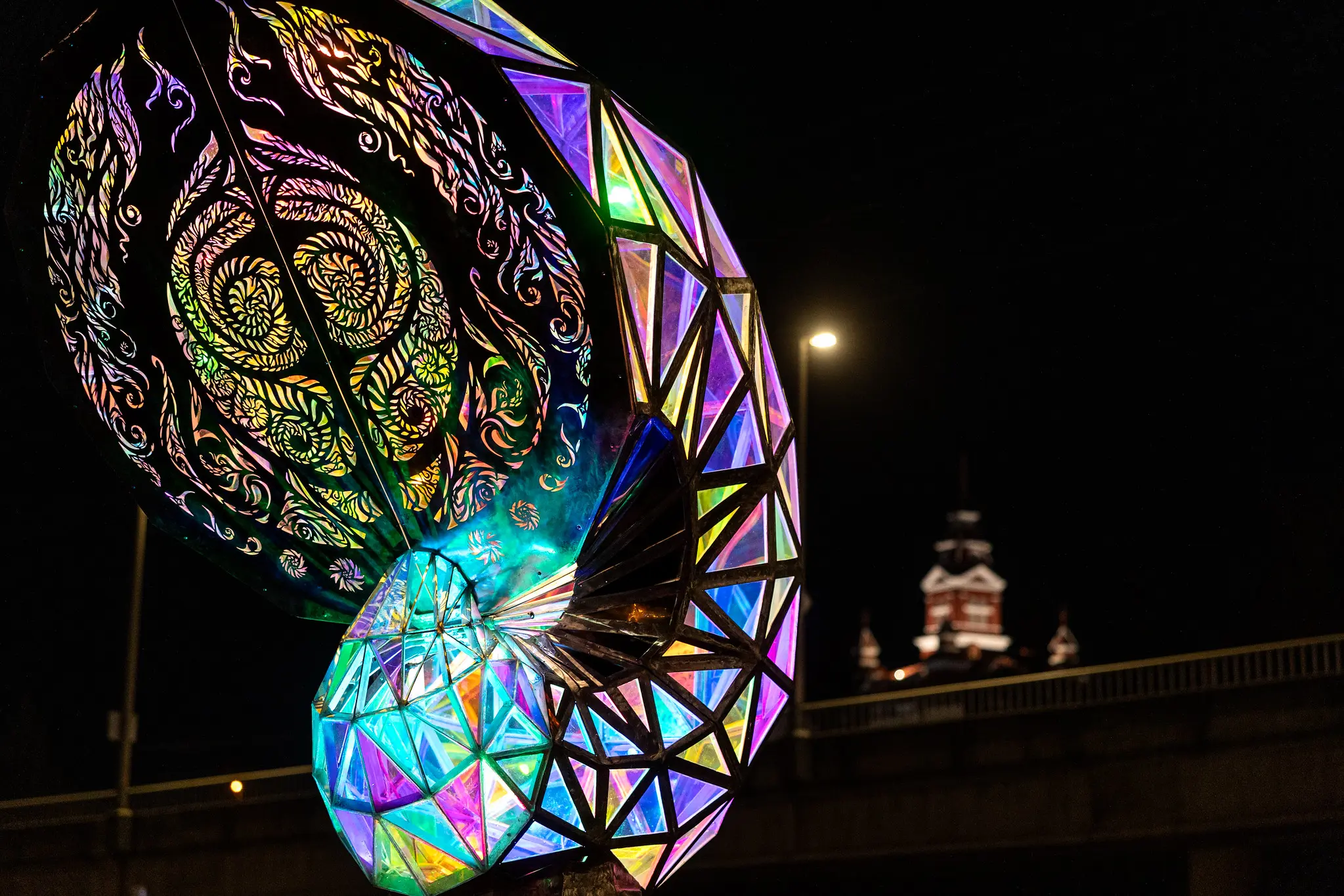 Colorfully lit up shell sculpture against a dark, night background.