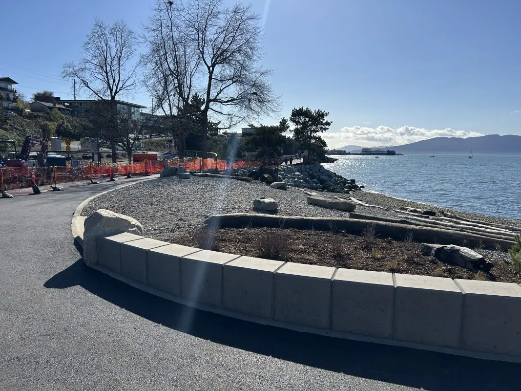 A rocky beach in front of a paved path