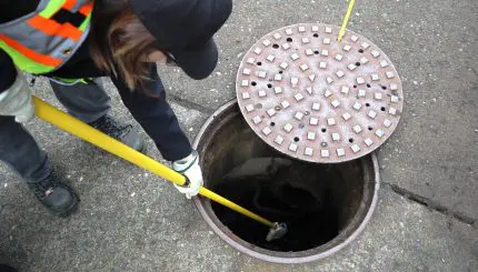 Person collecting sample out of a manhole