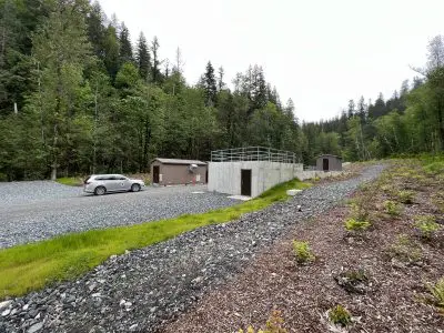 Newly planted plants in foreground. Vehicle and structures in background.