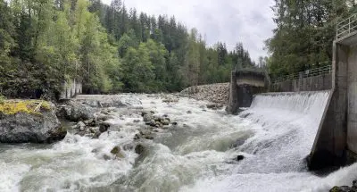 Restored river channel flowing freely through the location of the previous dam. Concrete remnants of the dam can be seen on either side of the river.