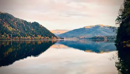 Sunset photo of Lake Whatcom with reflection of trees and hillsides in the lake water.