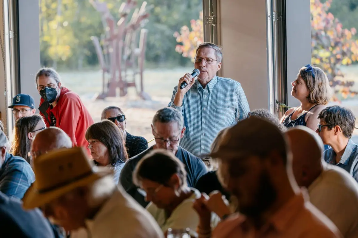 A man addresses a crowd holding a mic