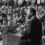 Martin Luther King delivering speech to crowd