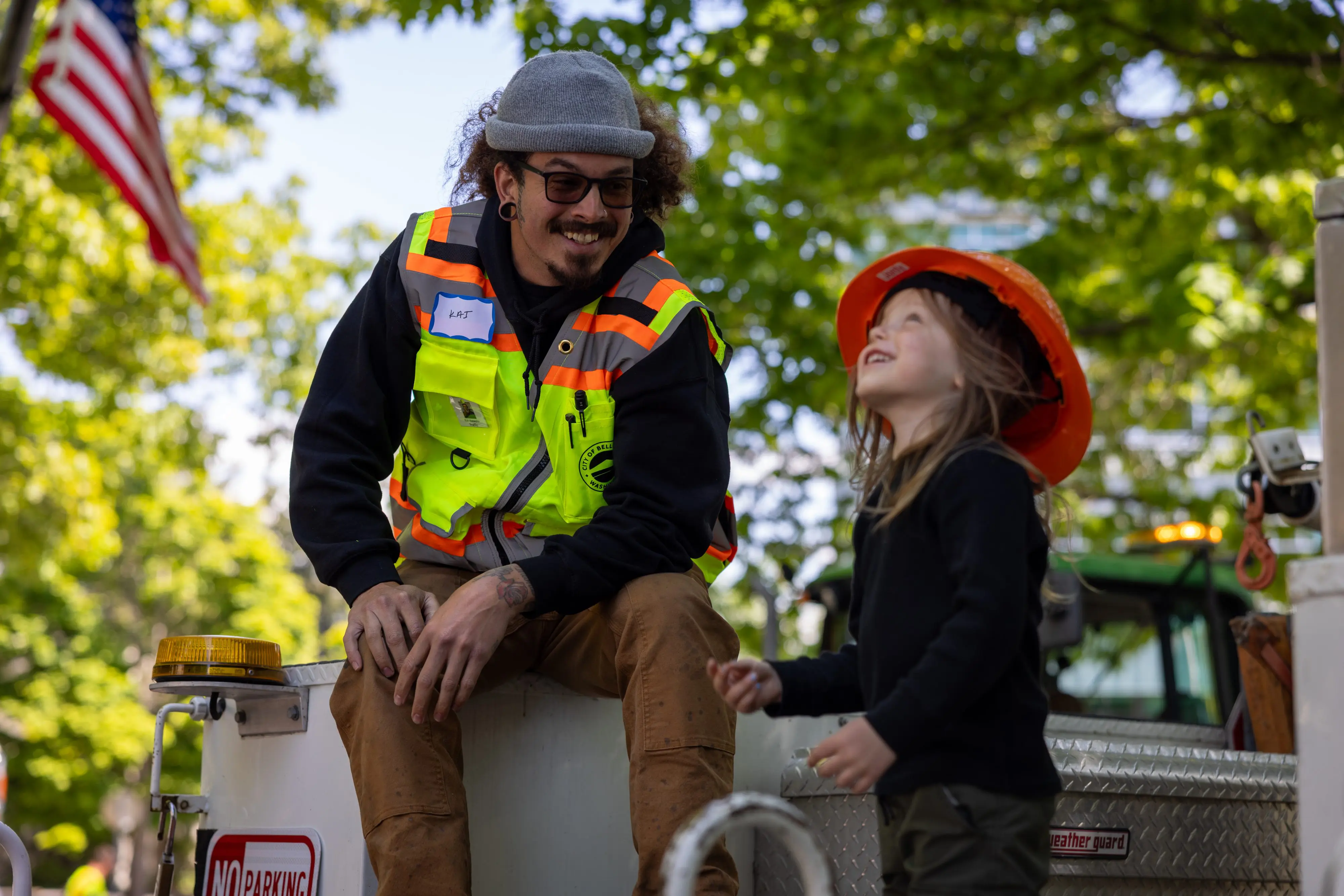 A construction worker and child smile on a truck