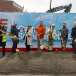 Bellingham Mayor Kim Lund and Community and Economic Development Manager Tara Sundin with members of the Old Town Village development team stand holding shovels to celebrate the beginning of a transformation in the Old Town District that will bring approximately 800 new housing units to the urban village. The project is more than 20 years in the making.