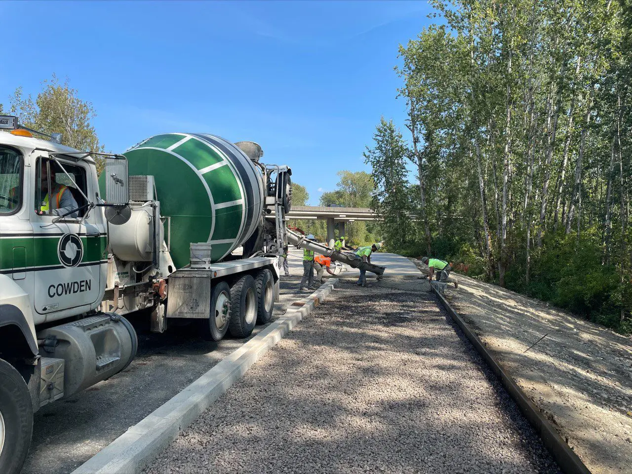 Construction workers guiding cement from cement truck into area for new sidewalk