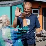 Two people high-five in front of several colorful tiny houses