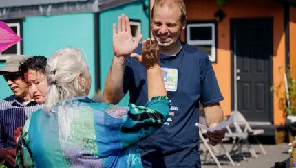 Two people high-five in front of several colorful tiny houses