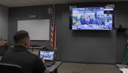 A police officer holds a controller and watches a tv screen showing a map