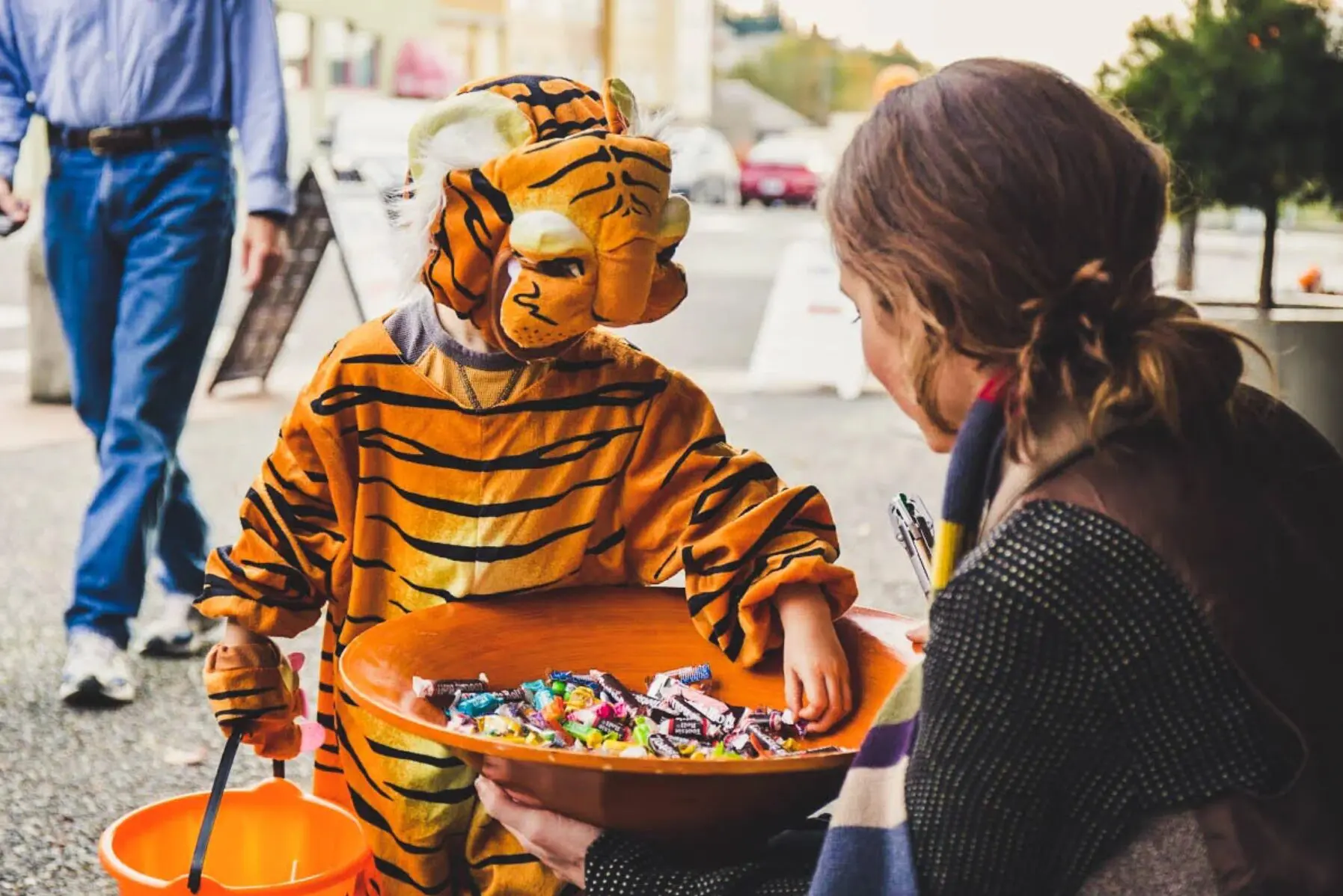 A child in a tiger costume trick-or-treats.