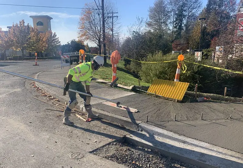 Worker using tool to flatten wet cement for new sidewalk