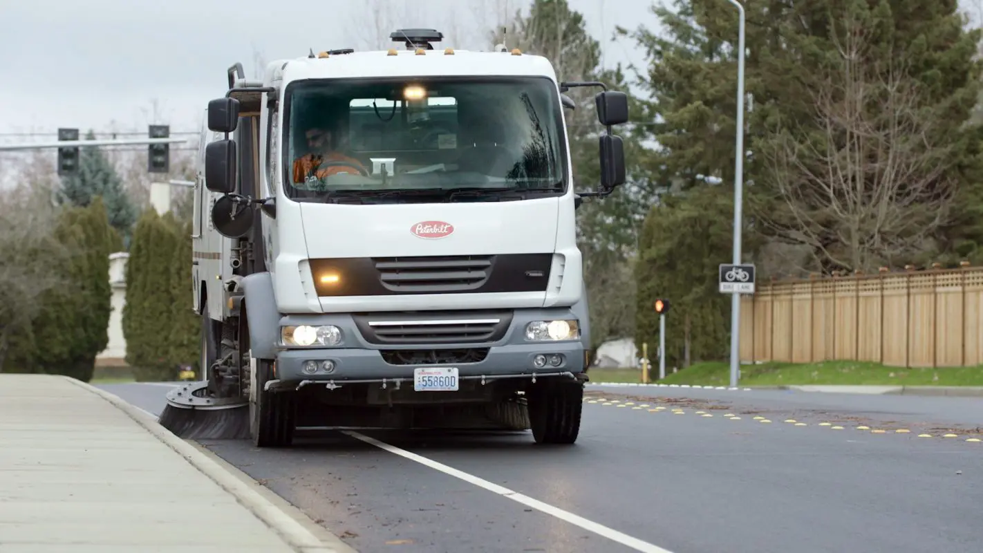 Street sweeper truck cleaning a roadway.