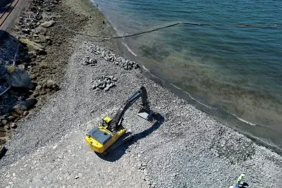 Excavator moving rock on shoreline