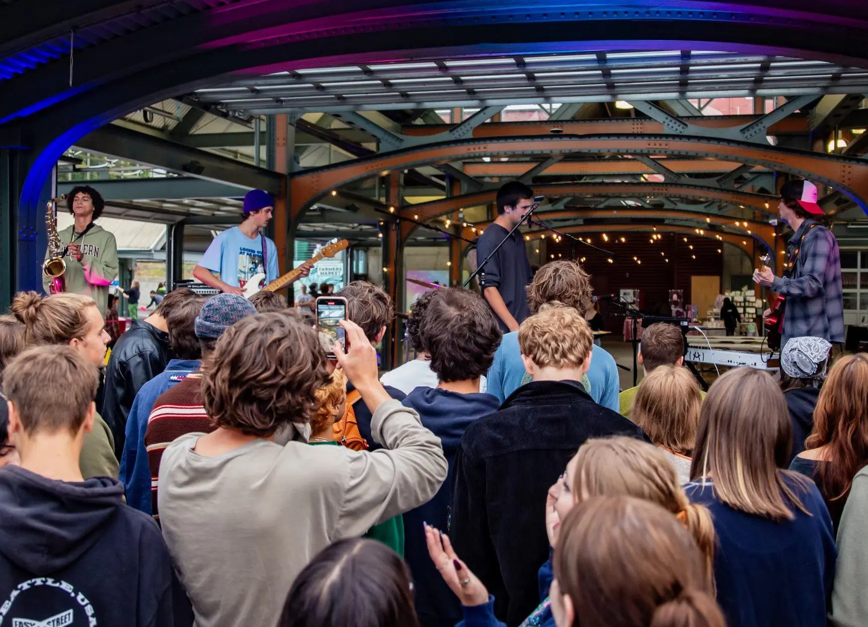 People gathered at a concert looking up at a stage where musicians play.