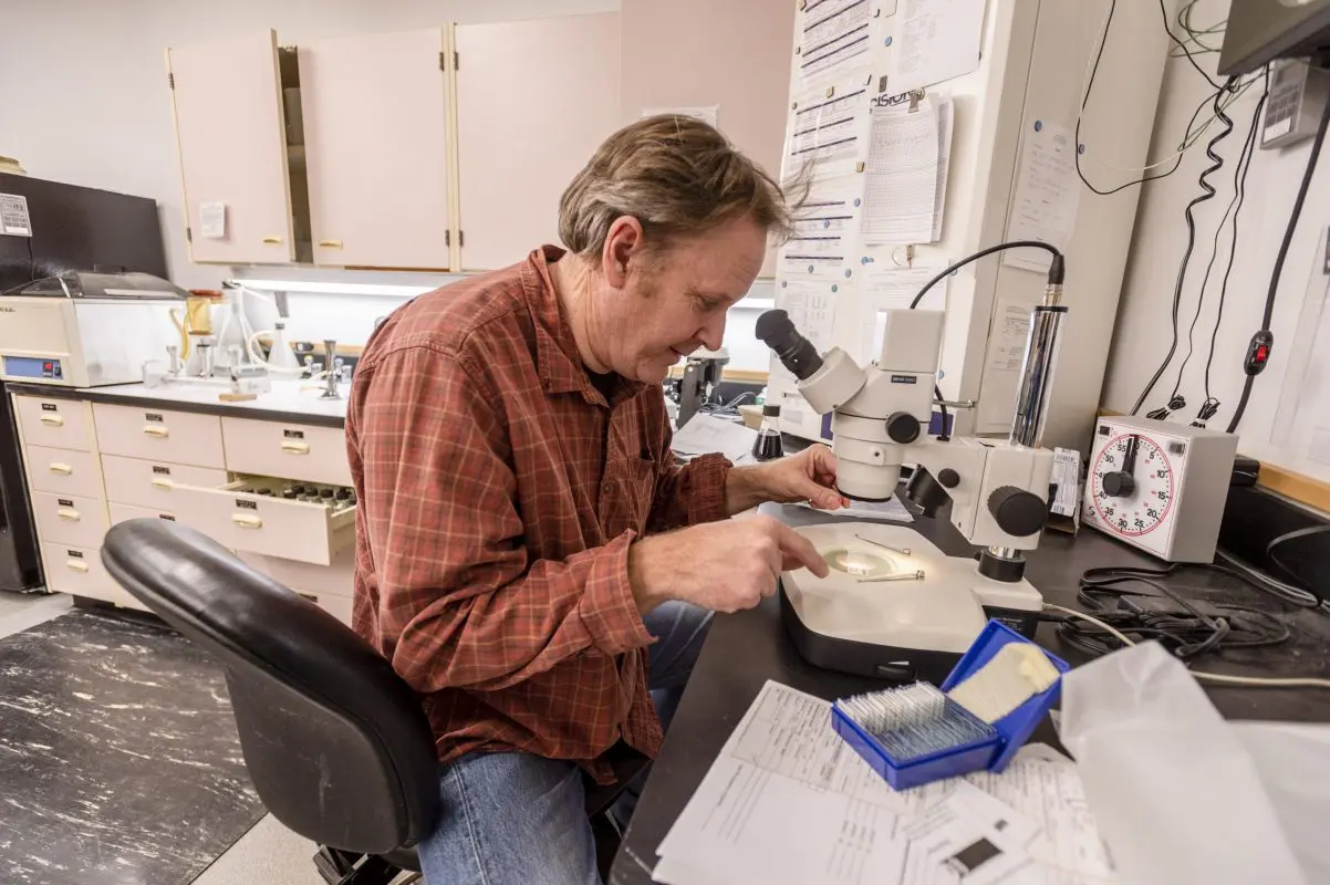 Man looking through a microscope at water sample