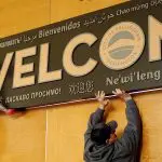 People install a sign that says "Welcome"