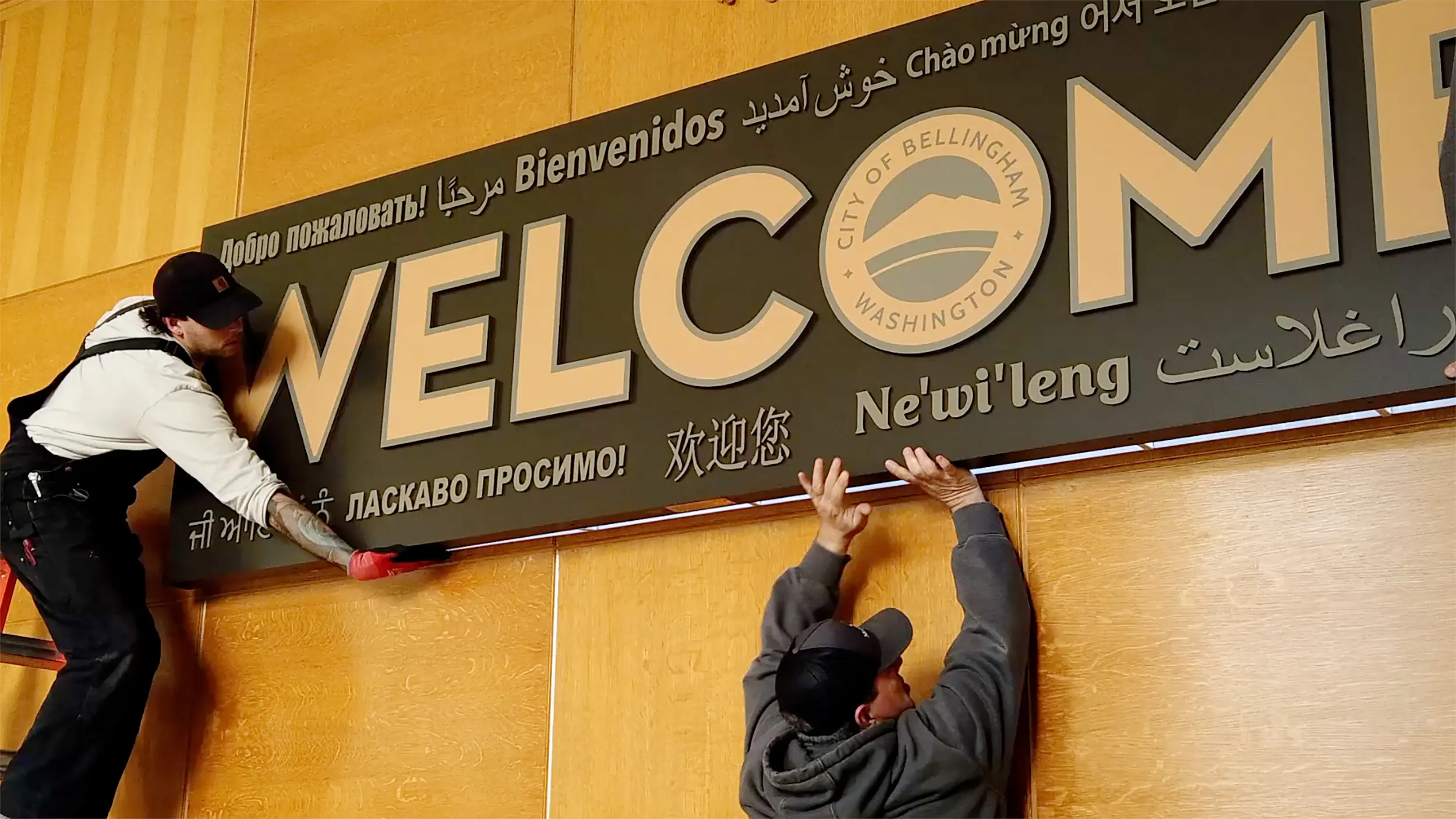 People install a sign that says "Welcome"