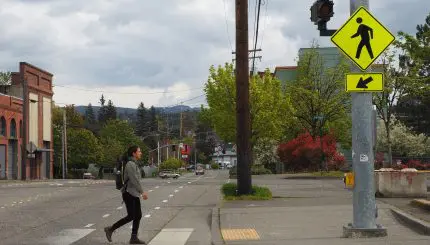 Person walking through hashed crosswalk with flashing light
