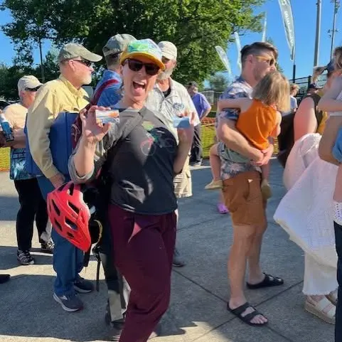 A woman in a crowd smiles while holding her library card