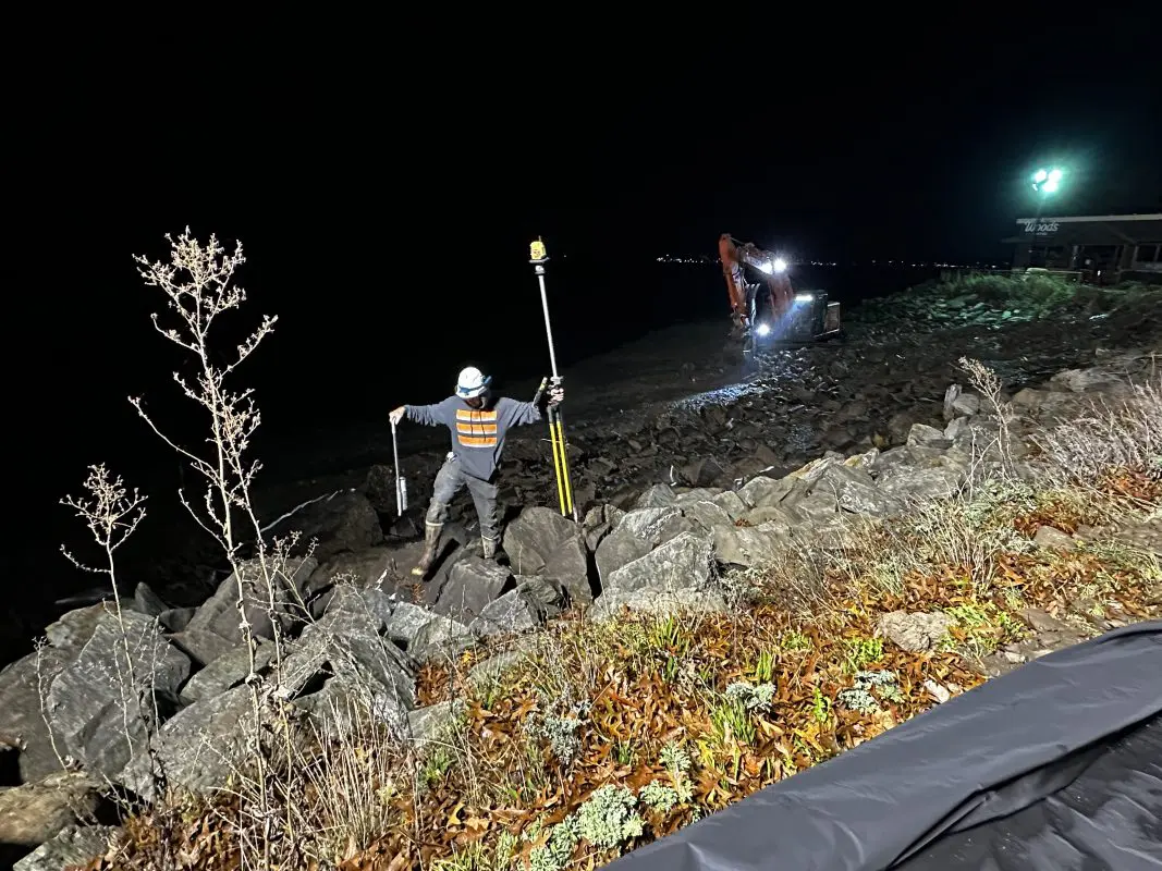 A man climbs rocks at night on a beach