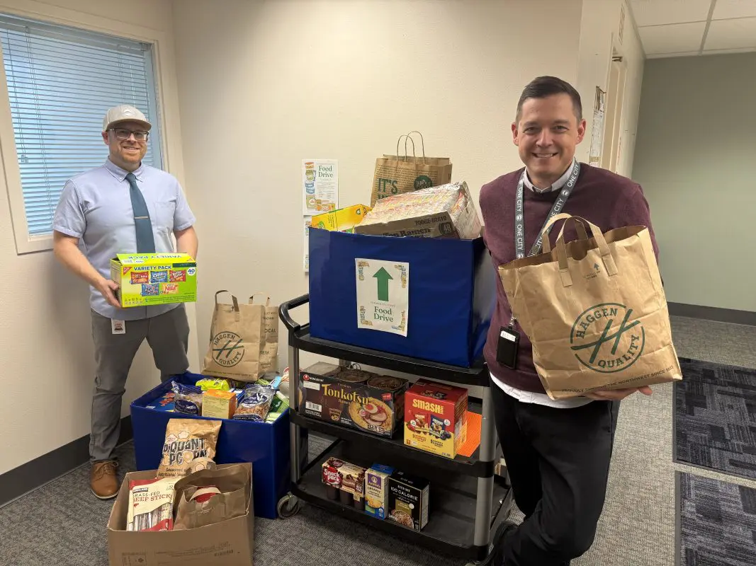 Two men pose with a cart full of food donations