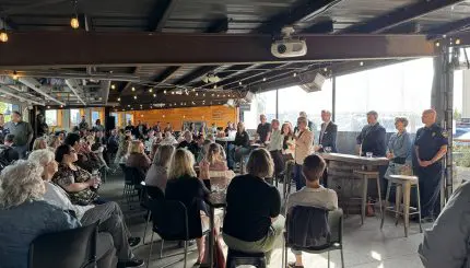 A large seated crowd in a bar with a panel of people at the front