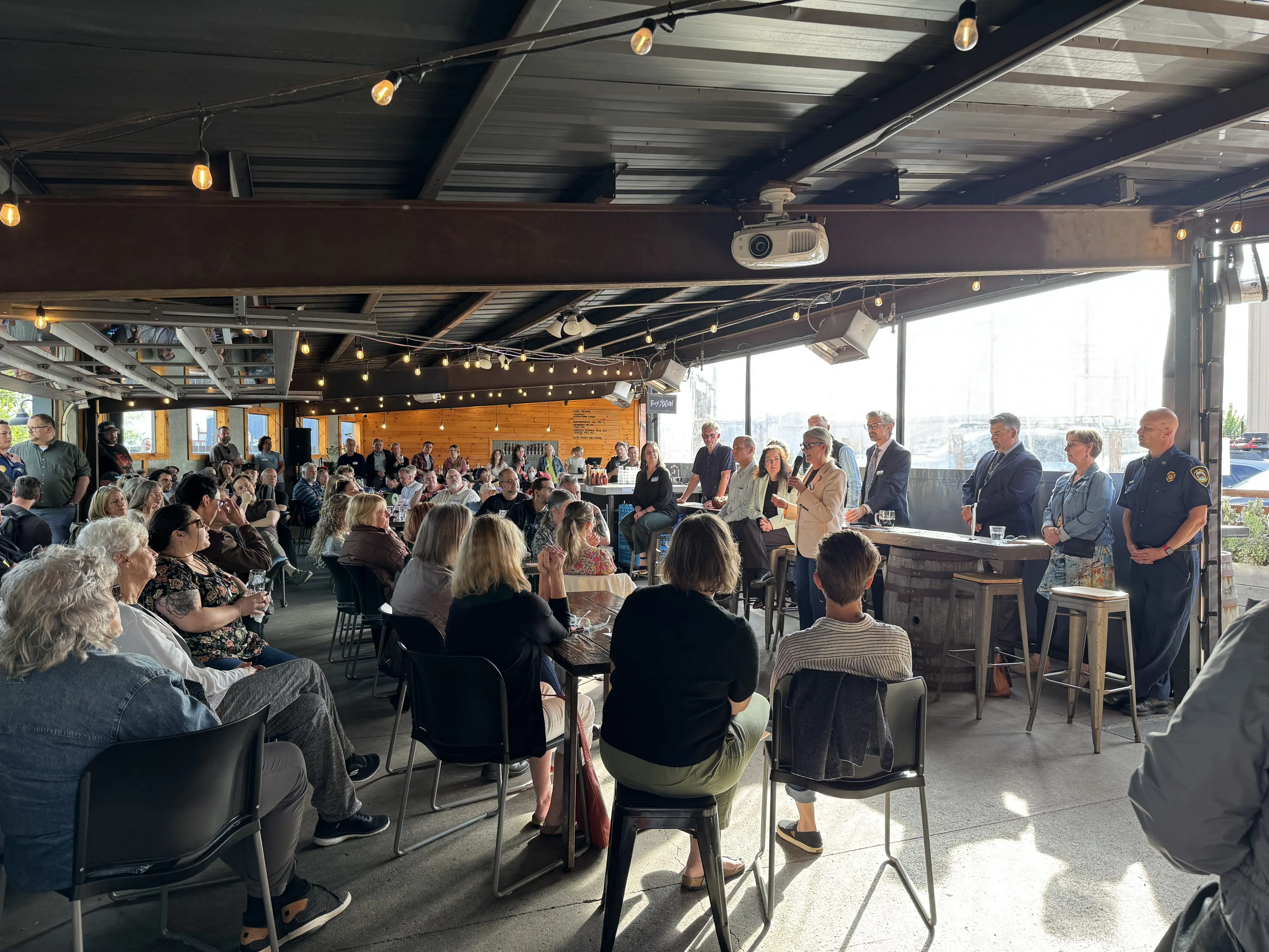 A large seated crowd in a bar with a panel of people at the front