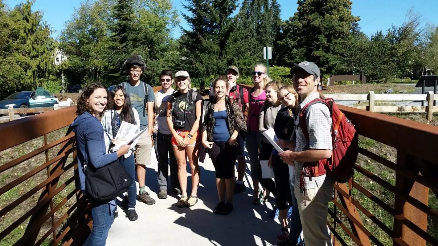 Group of people on a tour standing on a bridge smiling.